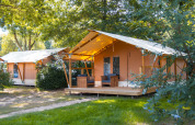 Foto de tiendas safari Slow Lodge en Camping Seasonova du Chêne en Francia, rodeadas de árboles y vegetación.