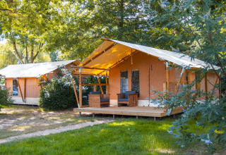 Foto de tiendas safari Slow Lodge en Camping Seasonova du Chêne en Francia, rodeadas de árboles y vegetación.