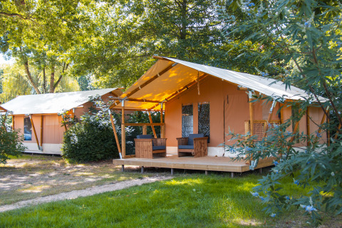 Safari-Zelt Slow Lodge auf dem Campingplatz Seasonova du Chêne in Frankreich, umgeben von Bäumen und Grün.