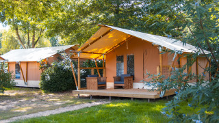 Foto de tiendas safari Slow Lodge en Camping Seasonova du Chêne en Francia, rodeadas de árboles y vegetación.