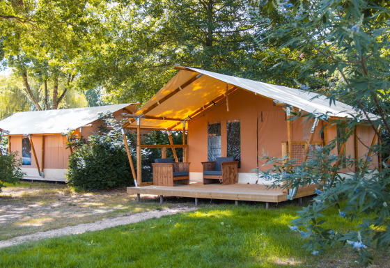 Safari-Zelt Slow Lodge auf dem Campingplatz Seasonova du Chêne in Frankreich, umgeben von Bäumen und Grün.