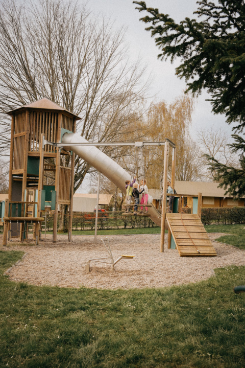 Bambini che giocano in un parco giochi con scivolo e altalene al Camping Belle-Vue 2000 a Echternach, Lussemburgo.