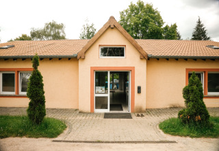 Indgang til en bygning i Camping Belle-Vue 2000, omgivet af træer og grønne områder i Echternach, Luxembourg.