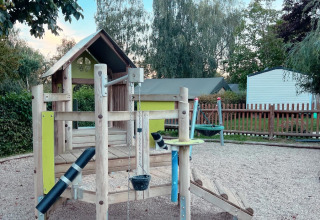 Playground at Camping Belle-Vue 2000 with wooden climbing structure and swings in Echternach, Luxembourg.