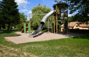 Parco giochi con scivolo e torre da arrampicata al Camping Belle-Vue 2000 a Echternach, Lussemburgo, circondato dal verde.