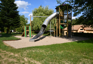 Legeplads med rutsjebane og klatretårn på Camping Belle-Vue 2000 i Echternach, Luxembourg, omgivet af grønne træer.