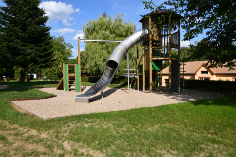 Spielplatz mit Rutsche und Kletterturm im Camping Belle-Vue 2000 in Echternach, Luxemburg, umgeben von Bäumen.