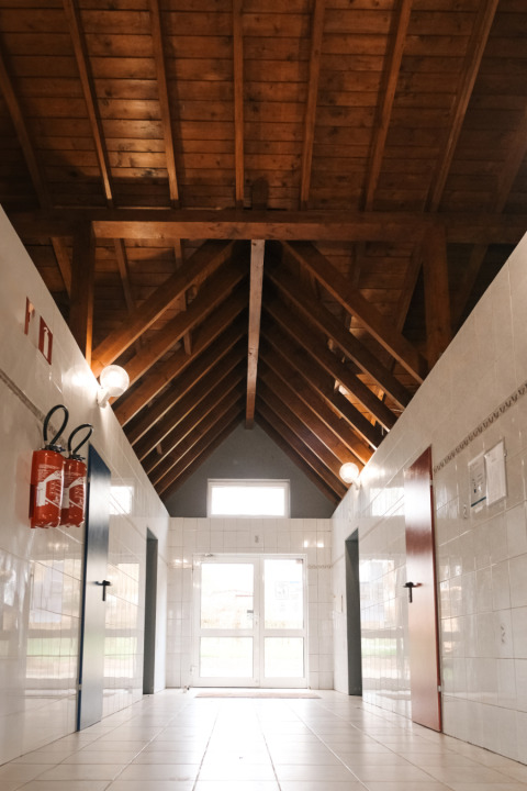 Corridoio interno con soffitto alto in legno e piastrelle bianche al Camping Belle-Vue 2000, Echternach, Lussemburgo.