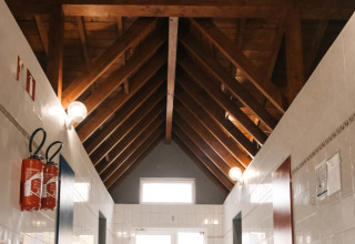 Corridoio interno con soffitto alto in legno e piastrelle bianche al Camping Belle-Vue 2000, Echternach, Lussemburgo.