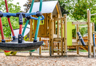 Parco giochi colorato con altalene e casetta in legno a Camping Belle-Vue 2000, Echternach, Lussemburgo.