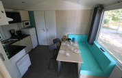 Interior of Mobilhome Loggia at Camping Belle-Vue 2000 showing kitchen, table, and turquoise seating.