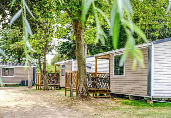 Mobilhome Loggia al Camping Belle-Vue 2000 in Lussemburgo, bungalow immersi nella natura tra alberi ombrosi.
