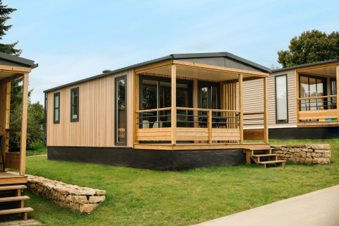 Contemporary Mobilhome O'Hara Living chalet featuring a wood facade and covered porch on a grassy plot.