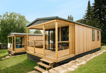 Chalet moderne en bois Mobilhome O'Hara Living au Camping Belle-Vue 2000 au Luxembourg entouré de verdure.