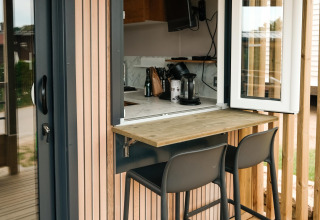 Outdoor-Sitzbereich mit zwei Barstühlen am Fenster, fotografiert im Mobilhome O'Hara Living, Camping Belle-Vue 2000.