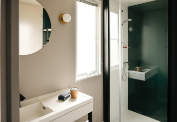 Modern bathroom at Mobilhome O'Hara Living in Camping Belle-Vue 2000, Luxembourg, showing sink, mirror, and shower.