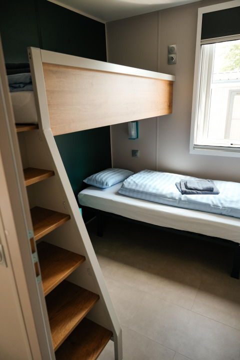 Chambre Mobilhome O'Hara Living avec lits superposés, escalier et fenêtre au Camping Belle-Vue 2000 au Luxembourg.