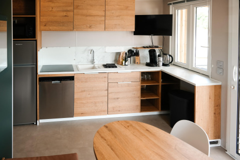 Modern kitchen with wooden cabinets, white countertops, appliances, and window in Mobilhome O'Hara Living chalet.