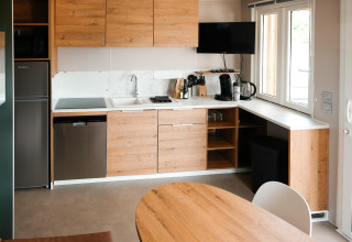 Moderne køkken med træskabe, hvide bordplader, vindue, TV og husholdningsapparater i Mobilhome O'Hara Living.