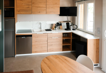 Cuisine moderne avec placards en bois, plans de travail blancs, appareils et fenêtre au Mobilhome O'Hara Living.