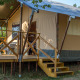 Vista de la Safari tent XL con terraza elevada de madera, escaleras y asientos al aire libre rodeados de naturaleza.