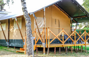 Safari-Zelt XL auf Camping Belle-Vue 2000 in Luxemburg, mit Holzveranda und Sitzmöglichkeiten draußen.