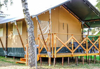 Safari-Zelt XL auf Camping Belle-Vue 2000 in Luxemburg, mit Holzveranda und Sitzmöglichkeiten draußen.