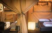 Interior de una tienda Safari XL con literas y cama doble en Camping Belle-Vue 2000 en Luxemburgo.