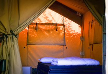 Interno di una tenda Safari XL al Camping Belle-Vue 2000 in Lussemburgo con letto comodo e luce calda.
