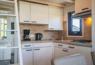 Moderna cocina pequeña en Tiny House de De Rijp, Países Bajos, con cafetera, hervidor y cocina de gas.