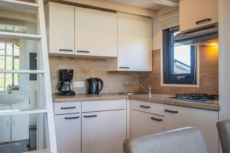 Moderna cocina pequeña en Tiny House de De Rijp, Países Bajos, con cafetera, hervidor y cocina de gas.