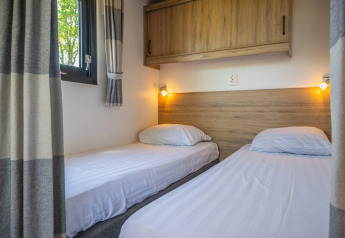 Twee eenpersoonsbedden met wit linnengoed in Tiny House bij De Rijp, Nederland, houten kast en raam.