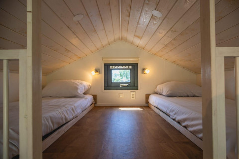 Twee lage bedden in een knusse loftkamer met houten plafond in Tiny House bij De Rijp, Nederland.