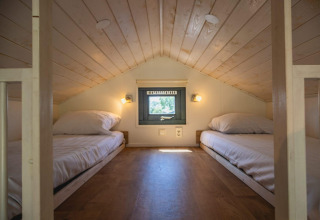 Dos camas bajas en un acogedor altillo con techo de madera en Tiny House en De Rijp, Países Bajos.