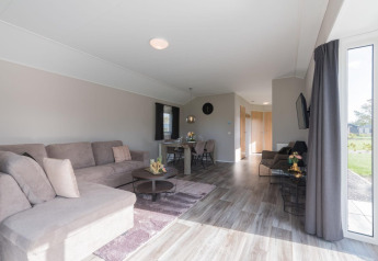 Lichte, ruime leefruimte in een Velthorst lodge in De Rijp, Nederland, met zetel, eettafel en grote ramen.