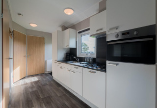 Cocina moderna en una cabaña de Velthorst en De Rijp, Países Bajos, con gabinetes blancos y puertas de madera.