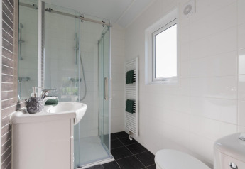 Moderne badkamer met glazen douche, wastafel en toilet in lodge Velthorst te De Rijp, Nederland.