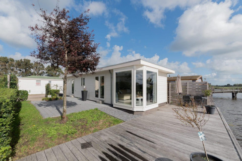 Moderne Velthorst-Lodge am Wasser in De Rijp, Niederlande, mit Holzterrasse und großen Fenstern.