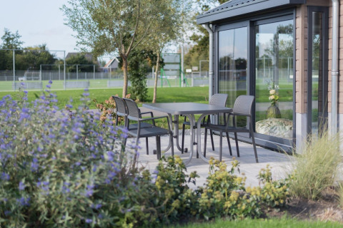 Terrasse am Velthorst-Lodge in De Rijp, Niederlande, mit Tisch, Stühlen und Gartenblick.