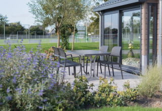 Terrasse am Velthorst-Lodge in De Rijp, Niederlande, mit Tisch, Stühlen und Gartenblick.