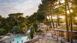 Uitzicht op vakantiepark Huttopia Arcachon met zwembad, speeltuin en dennenbomen in Nouvelle-Aquitaine, Frankrijk.