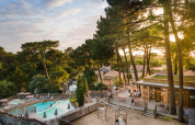 Vista del villaggio vacanze Huttopia Arcachon con piscina, parco giochi e pini in Nouvelle-Aquitaine, Francia.