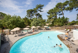 Buitenzwembad met houten terras en ligstoelen in vakantiepark Huttopia Arcachon, Nouvelle-Aquitaine, Frankrijk.
