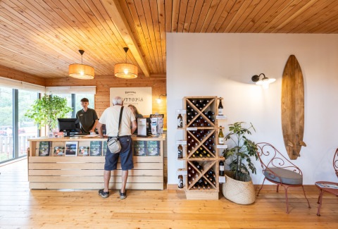 Recepción del parque vacacional Huttopia Arcachon en Nouvelle-Aquitaine, Francia, con interiores de madera y botellero.