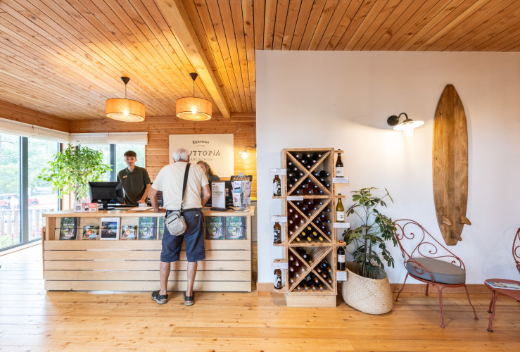 Reception area at Huttopia Arcachon holiday park in Nouvelle-Aquitaine, France, with wood interiors and wine rack.