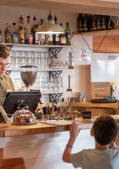 Un barista atiende a una familia en la recepción de Huttopia Arcachon en Nouvelle-Aquitaine, Francia.