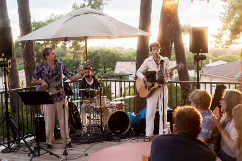 Concierto al aire libre en el parque vacacional Huttopia Arcachon en Francia, con músicos y público.