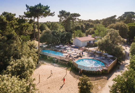 Luftfoto af ferieparken Huttopia Oléron les Pins med pool, volleyballbane og omgivet af skov i Frankrig.