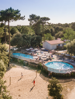 Luchtfoto van vakantiepark Huttopia Oléron les Pins in Frankrijk met zwembad, volleybal en pijnbomen.
