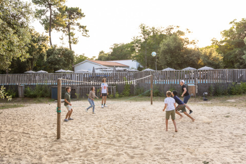 Niños juegan voleibol de playa en la arena en Huttopia Oléron les Pins, parque vacacional en Nouvelle-Aquitaine, Francia.